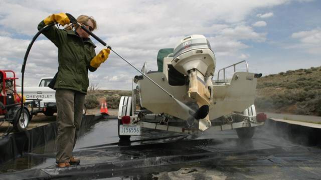 A person sprays a boat down to clean it